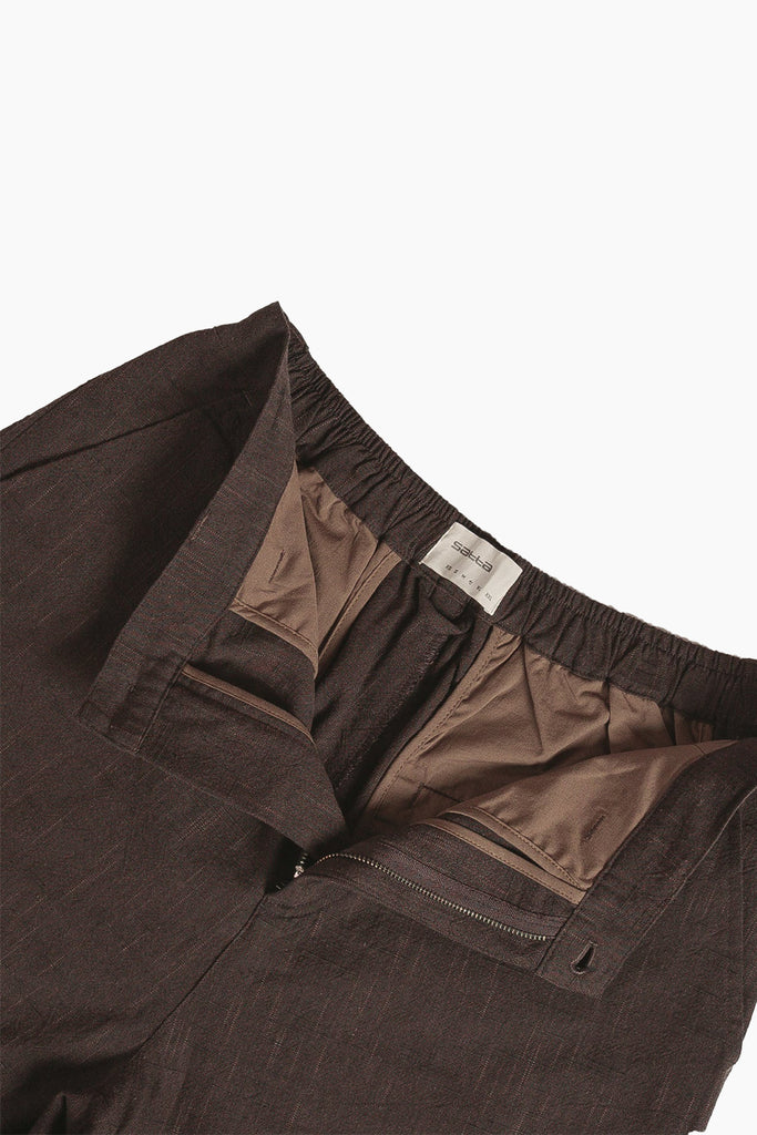 satta slow pant detail photo of button fly closure exposing the inside of the pants pocket liner and size tag with elasticated back.